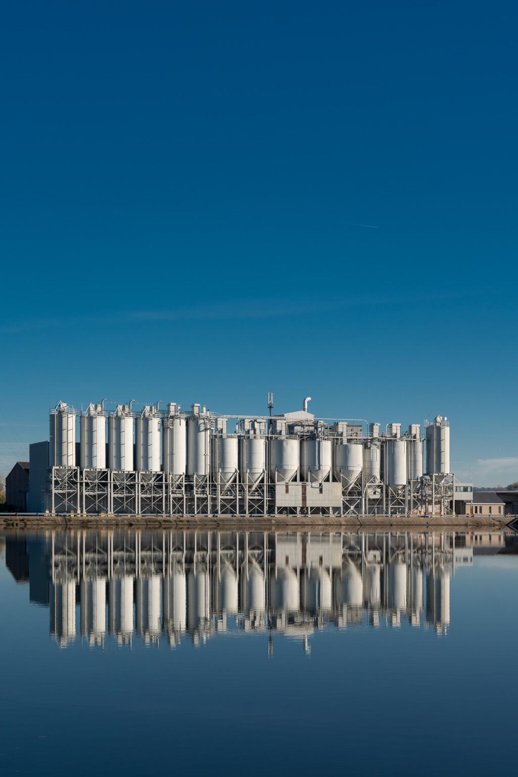 Industrieanlage am Wasser unter weitem blauem Himmel